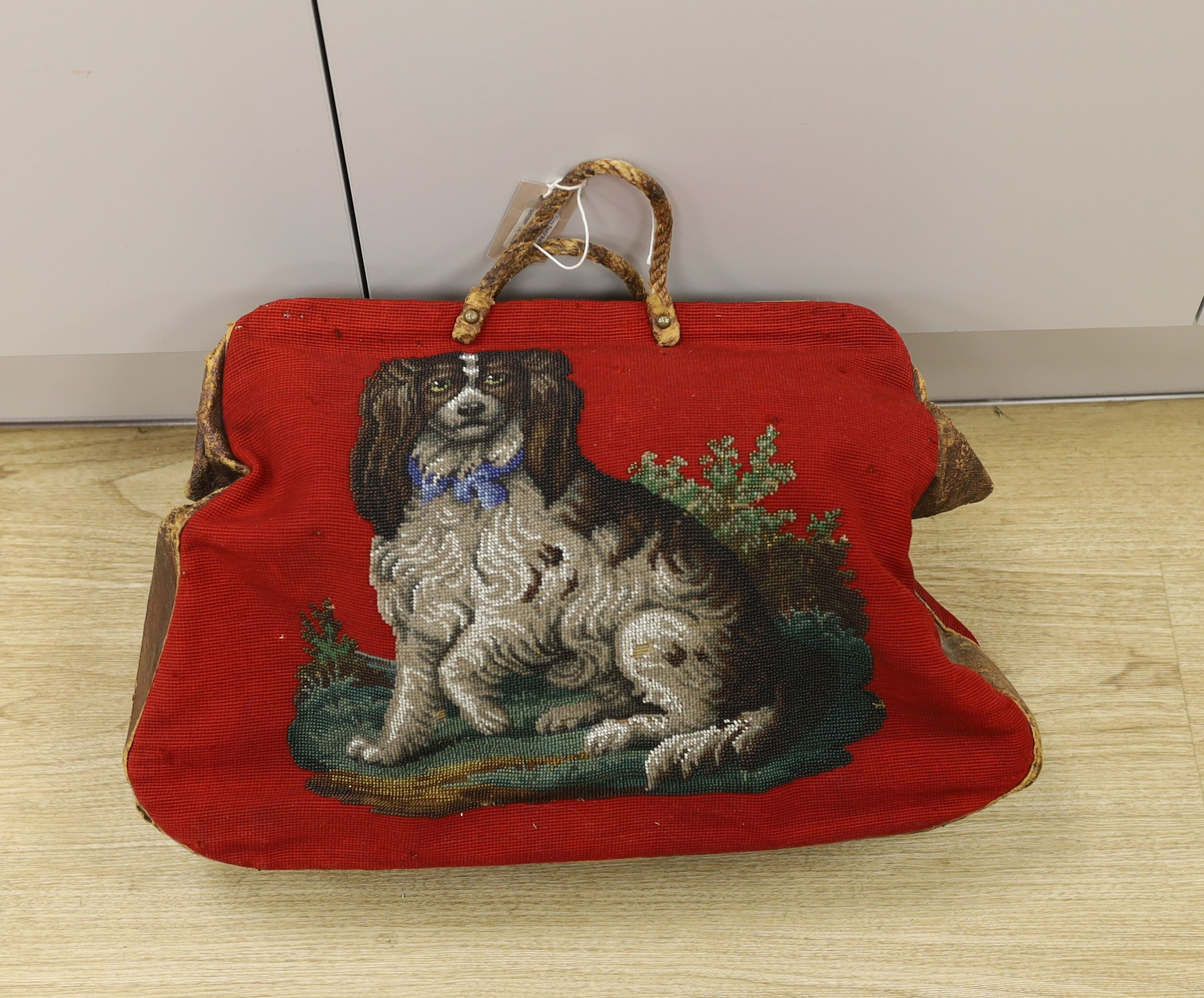 A 19th century Berlin beadwork and leather travel bag, designed one side with a King Charles Spaniel and other with a Terrier and message ‘Bon Voyage’, 46 cms wide x 35 high.